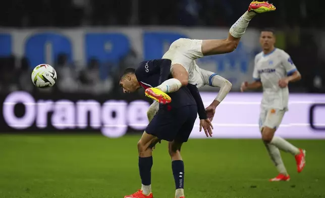 Marseille's Quentin Merlin jumps over PSG's Achraf Hakimi during the French League One soccer match between Marseille and Paris at the Velodrome stadium in Marseille, south of France, Sunday, March 31, 2024. (AP Photo/Daniel Cole)