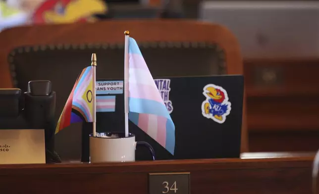 Small transgender rights flags sit on the desk in the Kansas House chamber for Rep. Allison Hougland, D-Olathe, during a break in the House's daylong session, Monday, April 29, 2024, at the Statehouse in Topeka, Kan. Hougland, other Democrats, and a few Republicans have prevented the GOP-controlled Legislature from overriding Democratic Gov. Laura Kelly's veto of a proposed ban on gender-affirming care for transgender minors. (AP Photo/John Hanna)