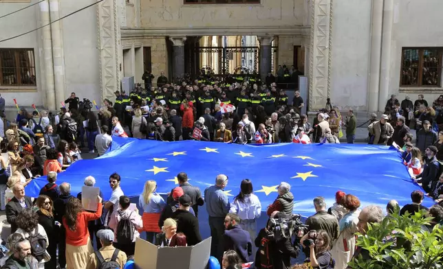 Protestors with a giant EU flag gather outside the parliament building in Tbilisi, Georgia, on Monday, April 15, 2024 to protest against the "the Russian law" as it is similar to a law that Russia uses to stigmatize independent news media and organizations seen as being at odds with the Kremlin. The governing party in the country of Georgia has submitted to parliament a draft law calling for media and non-commercial organizations to register as being under foreign influence if they receive more than 20% of their budget from abroad. (AP Photo/Shakh Aivazov)