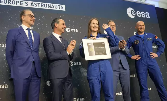 Katherine Bennell-Pegg of Australia waves as she shows her certificate at the candidates of the Class of 2022 graduation ceremony at the European Astronaut Centre in Cologne, Germany, Monday, April 22, 2024. ESA astronaut candidates Sophie Adenot of France, Pablo Alvarez Fernandez of Spain, Rosemary Coogan of Britain, Raphael Liegeois of Belgium and Marco Sieber of Switzerland took up duty at the European Astronaut Centre one year ago to be trained to the highest level of standards as specified by the International Space Station partners. Also concluding a year of astronaut basic training is Australian astronaut candidate Katherine Bennell-Pegg, who has trained alongside ESA's candidates. (AP Photo/Martin Meissner)