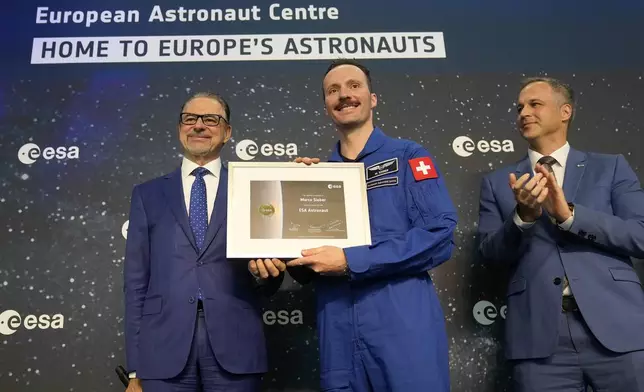 ESA director Josef Aschbacher, left, stands with Marco Sieber of Switzerland, center, at the candidates of the Class of 2022 graduation ceremony at the European Astronaut Centre in Cologne, Germany, Monday, April 22, 2024. ESA astronaut candidates Sophie Adenot of France, Pablo Alvarez Fernandez of Spain, Rosemary Coogan of Britain, Raphael Liegeois of Belgium and Marco Sieber of Switzerland took up duty at the European Astronaut Centre one year ago to be trained to the highest level of standards as specified by the International Space Station partners. Also concluding a year of astronaut basic training is Australian astronaut candidate Katherine Bennell-Pegg, who has trained alongside ESA's candidates. (AP Photo/Martin Meissner)