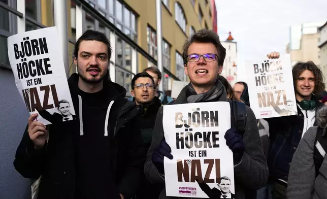 Protestor hold posters reading 'Bjoern Hoecke is a Nazi' outside the state court in Halle, Germany, Thursday, April 18, 2024. Bjoern Hoecke, goes on trial at the state court in Halle on charges related to his alleged use in a 2021 speech of a slogan used by the Nazis' SA stormtroopers. (AP Photo/Ebrahim Noroozi, Pool)