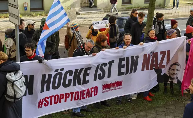Protestors hold a banner reading 'Bjoern Hoecke is a nazi' outside the state court in Halle, Germany, Thursday, April 18, 2024. Bjoern Hoecke, goes on trial at the state court in Halle on charges related to his alleged use in a 2021 speech of a slogan used by the Nazis' SA stormtroopers. (Fabrizio Bensch/Pool via AP)
