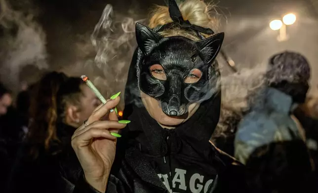 People smoke marijuana in front of the Brandenburg Gate during the 'Smoke-In' event in Berlin, Germany, Monday, April 1, 2024. Starting 1 April, Germany has legalised cannabis for personal use. As per the new law, Adults aged 18 and over will be allowed to carry up to 25 grams of cannabis for their own consumption. (AP Photo/Ebrahim Noroozi)