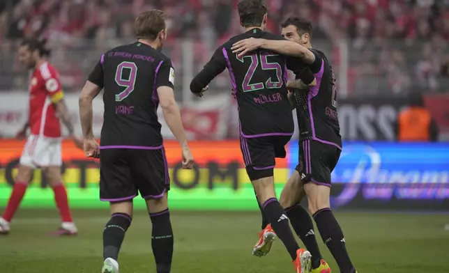 Bayern's Thomas Mueller celebrates with his teammate Leon Goretzka after scoring his side's third goal during the German Bundesliga soccer match between FC Union Berlin and Bayern Munich at the An der Alten Forsterei stadium in Berlin, Germany, Saturday, April 20, 2024. (AP Photo/Ebrahim Noroozi)