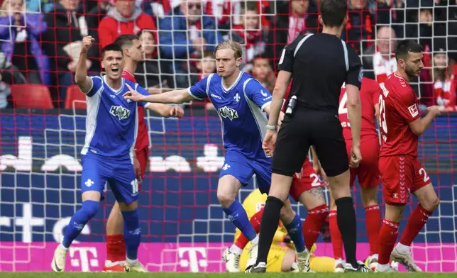 Darmstadt's Christoph Klarer, center, celebrates scoring their side's first goal of the game during the German Bundesliga soccer match between Darmstadt and FC Cologne at the RheinEnergieStadion in Cologne, Germany, Saturday April 20, 2024. (Marius Becker/dpa via AP)