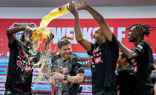 FILE - Leverkusen's Jonathan Tah, right, sprays beer on head coach Xabi Alonso after Bayer Leverkusen won the German Bundesliga title beating Werder Bremen in Leverkusen, Germany, Sunday, April 14, 2024. After the Bundesliga title, Tah has also the chance to win the German Cup and the Europa League this season with Leverkusen. He is also defender for Germany's national team. (AP Photo/Martin Meissner)