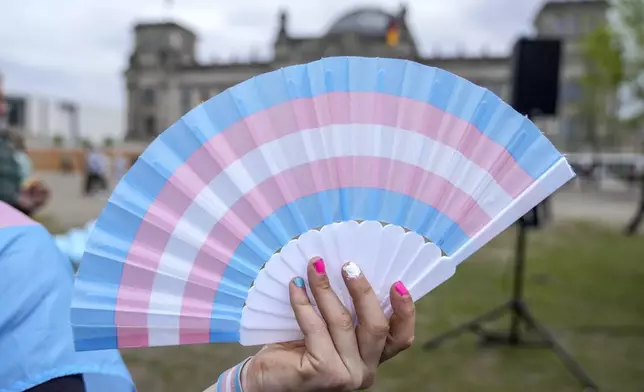 A demonstrator holds a fan during a protest demanding a law to protect the rights of the transgender community outside of the parliament Bundestag building in Berlin, Friday, April 12, 2024. German lawmakers on Friday approved legislation that will make it easier for transgender, intersex and nonbinary people to change their name and gender in official records. (AP Photo/Ebrahim Noroozi)