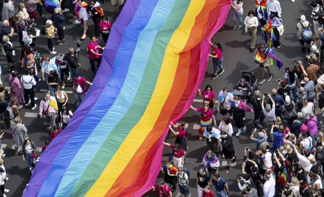 FILE - People hold a rainbow flag as they attend the 45th Berlin Pride Parade for Christopher Street Day (CSD) in Berlin, Germany, Saturday, July 22, 2023. German lawmakers are expected to vote on a government plan to make it easier for transgender, intersex and nonbinary people to change their name and gender in official documents. (Fabian Sommer/dpa via AP, File)