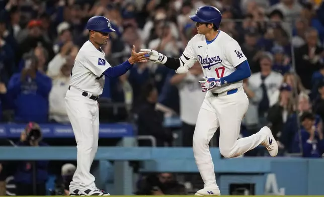 Los Angeles Dodgers designated hitter Shohei Ohtani (17) celebrates with third base coach Dino Ebel as he runs the bases after hitting a home run during the seventh inning of a baseball game against the San Francisco Giants in Los Angeles, Wednesday, April 3, 2024. (AP Photo/Ashley Landis)