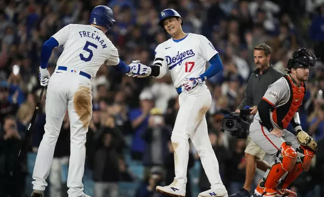 Los Angeles Dodgers designated hitter Shohei Ohtani celebrates with Freddie Freeman (5) after hitting a home run during the seventh inning of a baseball game against the San Francisco Giants in Los Angeles, Wednesday, April 3, 2024. (AP Photo/Ashley Landis)