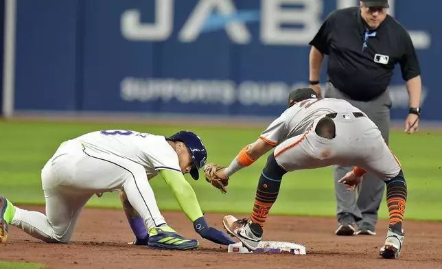 Tampa Bay Rays' Harold Ramírez, left, gets back safely ahead of the tag by San Francisco Giants second baseman Thairo Estrada after Ramirez over ran the base on an infield single by Amed Rosario during the second inning of a baseball game Friday, April 12, 2024, in St. Petersburg, Fla. (AP Photo/Chris O'Meara)