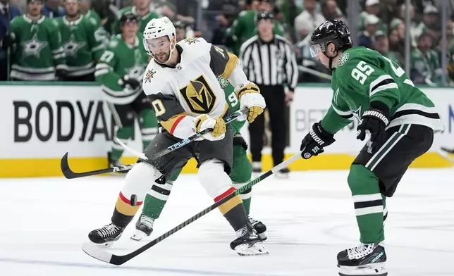 Vegas Golden Knights center Nicolas Roy (10) flips the puck forward over the stick of Dallas Stars' Matt Duchene (95) in the second period in Game 1 of an NHL hockey Stanley Cup first-round playoff series in Dallas, Monday, April 22, 2024. (AP Photo/Tony Gutierrez)