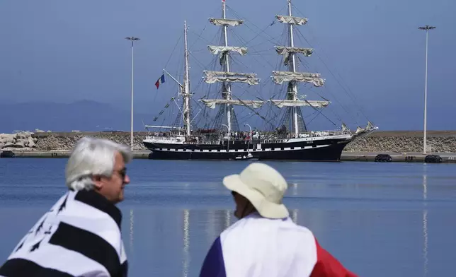 French visitors watch the historic Belem ship at the port of Katakolo, about 311 kilometers (194 miles) southwest of Athens, Greece, Monday, April 15, 2024. Built the same year the first modern Olympics were staged in Athens, in 1896, the Belem will carry the flame for the Paris games from the Greek capital's port of Piraeus to Marseille -- a former ancient Greek colony in southern France. (AP Photo/Thanassis Stavrakis)