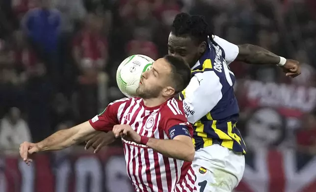 Olympiacos' Kostas Fortounis, left, and Fenerbahce's Bright Osayi-Samuel jump for the ball during the Europa Conference League quarter final first leg soccer match between Olympiacos and Fenerbahce at the Georgios Karaiskakis stadium, Piraeus port near Athens, Greece, Thursday, April 11, 2024. (AP Photo/Thanassis Stavrakis)