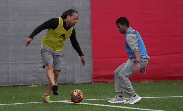 Former US soccer player Carli Lloyd, left, controls the ball as a young migrant tries to stop him during a soccer game at Olympiacos Training Center in Athens, Monday, April 22, 2024. Elite American athletes and coaches, including the former US soccer players Carli Lloyd and Cobi Jones, take part in the 2024 spring roster of U.S. Soccer Sports Envoys organized by the U.S. Department of State. (AP Photo/Thanassis Stavrakis)
