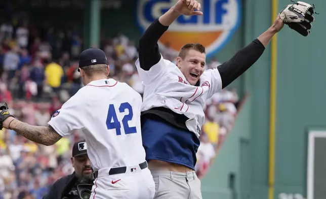 Former New England Patriots NFL football player Rob Gronkowski, right, reacts with Boston Red Sox's Tanner Houck, left, after spiking the ball instead of throwing it during the ceremonial first pitch before a baseball game against the Cleveland Guardians, Monday, April 15, 2024, in Boston. (AP Photo/Michael Dwyer)