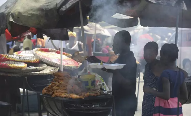 A vendor sells grilled chicken to customers in Port-au-Prince, Haiti, Monday, April 8, 2024. (AP Photo/Odelyn Joseph)