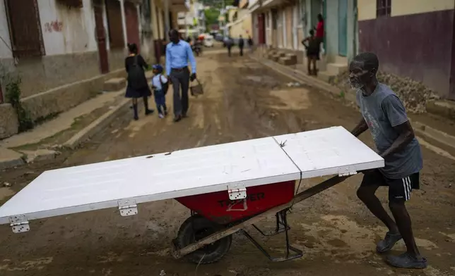 A man uses a wheelbarrow to transport a door, in Cap-Haitien, Haiti, Wednesday, April 17, 2024. (AP Photo/Ramon Espinosa)