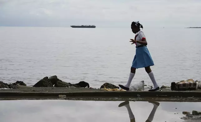 A girl walks alongside a body of water, in Cap-Haitien, Haiti, Wednesday, April 17, 2024. (AP Photo/Ramon Espinosa)