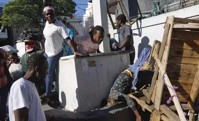 FILE - People look at a body after an overnight shooting in the Petion Ville neighborhood of Port-au-Prince, Haiti, March 18, 2024. (AP Photo/Odelyn Joseph, File)