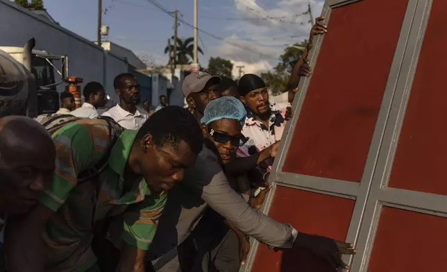 Neighbors raise a metal gate as they work to install as a barricade as protection against gangs, in the Petion-Ville neighborhood of Port-au-Prince, Haiti, Saturday, April 20, 2024. (AP Photo/Ramon Espinosa)