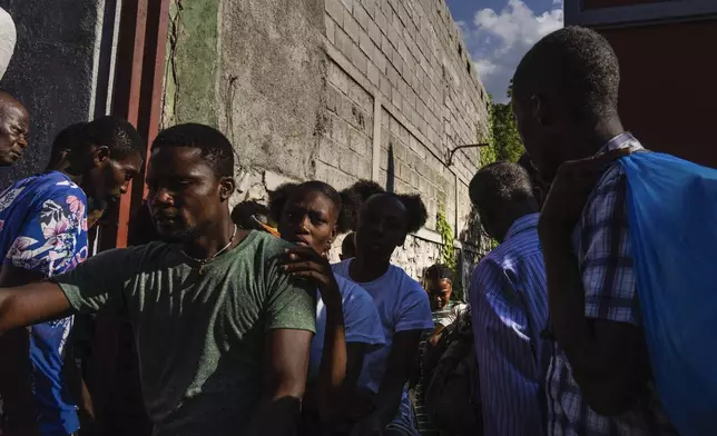 Neighbors pass in and out of a passageway as others erect a metal gate as protection against gangs, in the Petion-Ville neighborhood of Port-au-Prince, Haiti, Saturday, April 20, 2024. (AP Photo/Ramon Espinosa)