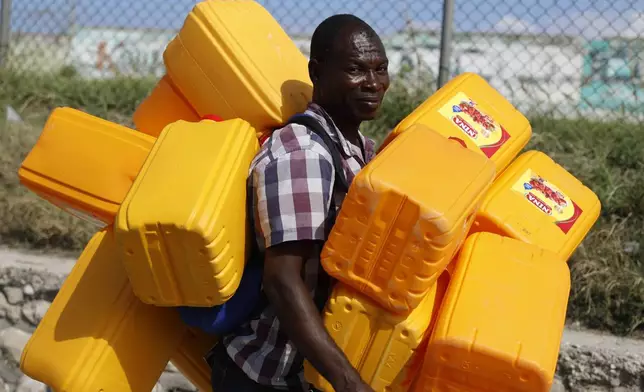 FILE - A vendor carries empty containers for fuel in Port-au-Prince, Haiti, March 6, 2024. (AP Photo/Odelyn Joseph, File)