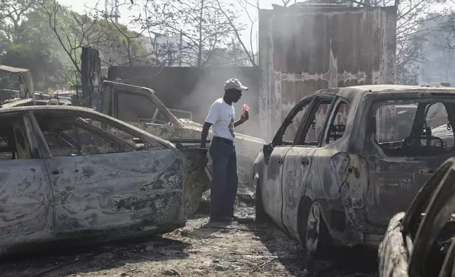 A man looks for salvageable items at a car mechanic shop that was set fire during gang violence in Port-au-Prince, Haiti, Monday, March 25, 2024. (AP Photo/Odelyn Joseph)