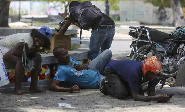People take cover from gunfire during clashes between police and gangs in the Champs de Mars area next to the National Palace in Port-au-Prince, Haiti, Monday, April 8, 2024. (AP Photo/Odelyn Joseph)