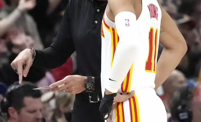 Atlanta Hawks coach Quin Snyder, left, talks to guard Trae Young during the first half of the team's NBA basketball play-in tournament game against the Chicago Bulls in Chicago, Wednesday, April 17, 2024. (AP Photo/Nam Y. Huh)