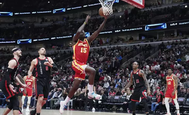 Atlanta Hawks center Clint Capela, right, drives to the basket past Chicago Bulls guard Alex Caruso, left, and center Nikola Vucevic during the first half of an NBA basketball game in Chicago, Monday, April 1, 2024. (AP Photo/Nam Y. Huh)