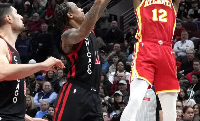 Atlanta Hawks forward De'Andre Hunter, right, shoots over Chicago Bulls center Nikola Vucevic, left, and forward DeMar DeRozan during the first half of an NBA basketball game in Chicago, Monday, April 1, 2024. (AP Photo/Nam Y. Huh)