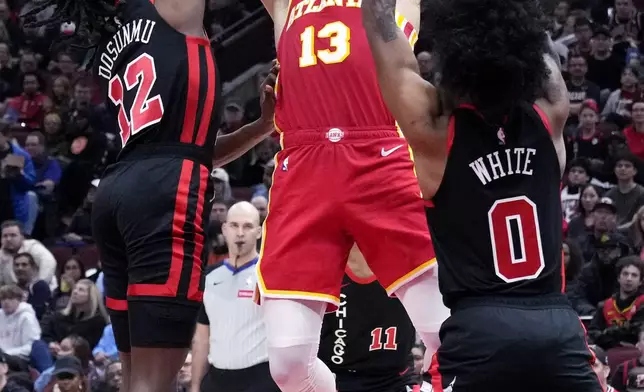 Atlanta Hawks guard Bogdan Bogdanovic, center, looks to pass as Chicago Bulls guard Ayo Dosunmu, left, and guard Coby White guard during the first half of an NBA basketball game in Chicago, Monday, April 1, 2024. (AP Photo/Nam Y. Huh)