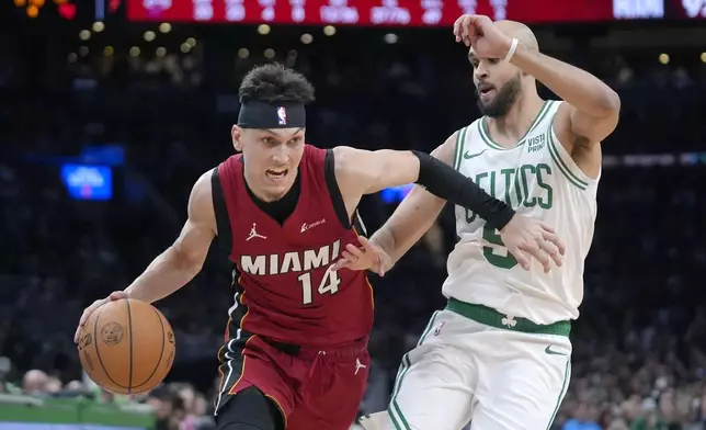 Miami Heat guard Tyler Herro (14) drives past Boston Celtics guard Derrick White, right, in the second half of Game 1 of an NBA basketball first-round playoff series, Sunday, April 21, 2024, in Boston. (AP Photo/Steven Senne)