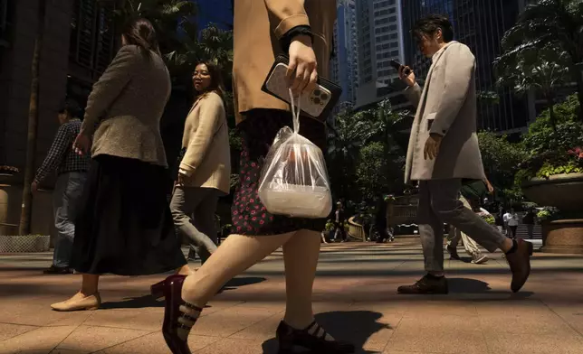 A pedestrian carries takeaway food plastic bag in Hong Kong, Wednesday, March 13, 2024. Hong Kong has long been a major producer and consumer of great food, and a great amount of plastic and Styrofoam to go with it. That’s going to change as new legislation aiming to stop the sale and distribution of Styrofoam products and single-use plastic cutlery went into effect on Monday, April 22, 2024. (AP Photo/Louise Delmotte)