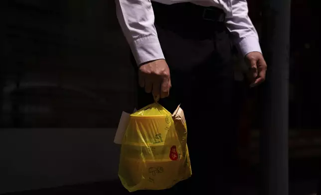 A pedestrian carries takeaway food plastic bag in Hong Kong, Thursday, April 11, 2024. Hong Kong has long been a major producer and consumer of great food, and a great amount of plastic and Styrofoam to go with it. That’s going to change as new legislation aiming to stop the sale and distribution of Styrofoam products and single-use plastic cutlery went into effect on Monday, April 22, 2024.(AP Photo/Louise Delmotte)