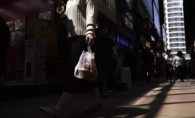A pedestrian carries takeaway food plastic bag in Hong Kong, Wednesday, March 13, 2024. Hong Kong has long been a major producer and consumer of great food, and a great amount of plastic and Styrofoam to go with it. That’s going to change as new legislation aiming to stop the sale and distribution of Styrofoam products and single-use plastic cutlery went into effect on Monday, April 22, 2024.(AP Photo/Louise Delmotte)