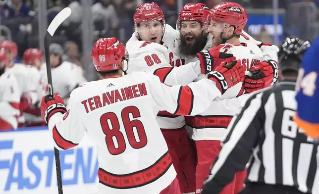 Carolina Hurricanes' Brent Burns, second from right, celebrates with Jaccob Slavin, right, Teuvo Teravainen (86) and Martin Necas (88) after scoring a goal against the. New York Islanders during the first period of Game 3 of an NHL hockey Stanley Cup first-round playoff series Thursday, April 25, 2024, in Elmont, N.Y. (AP Photo/Frank Franklin II)