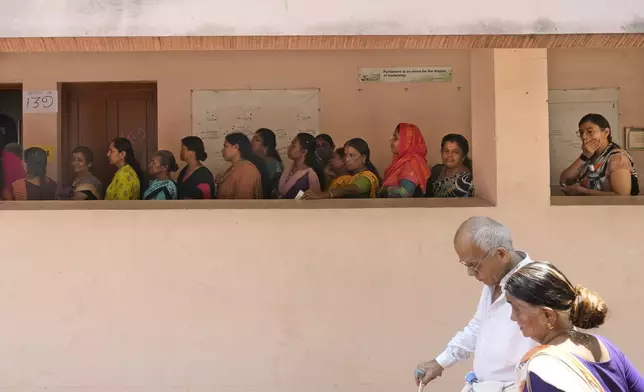 An elderly couple arrive as others wait in a queue to cast their vote during the second phase of national election in Palakkad, Kerala, India, Friday, April 26, 2024. (AP Photo/Manish Swarup)