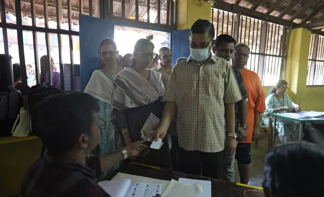 A man shows his identity papers to a polling official as people queue up to vote during the second round of voting in the six-week-long national election near Palakkad, in Indian southern state of Kerala, Friday, April 26, 2024. (AP Photo/Manish Swarup)
