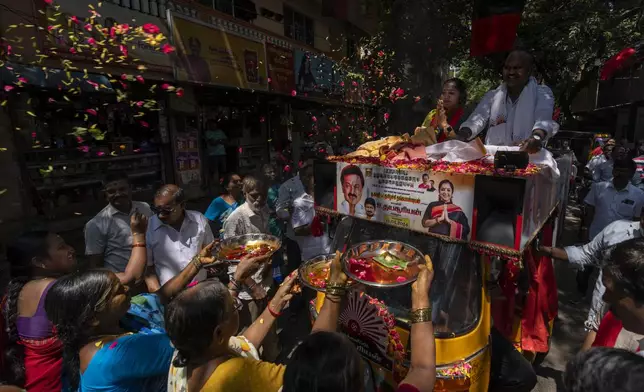 Women do rituals as they welcome Dravida Munnetra Kazhagam (DMK) party candidate Thamizhachi Thangapandian, left, riding on top of a auto rickshaw during a roadshow ahead of country's general elections, in the southern Indian city of Chennai, April 15, 2024. (AP Photo/Altaf Qadri)