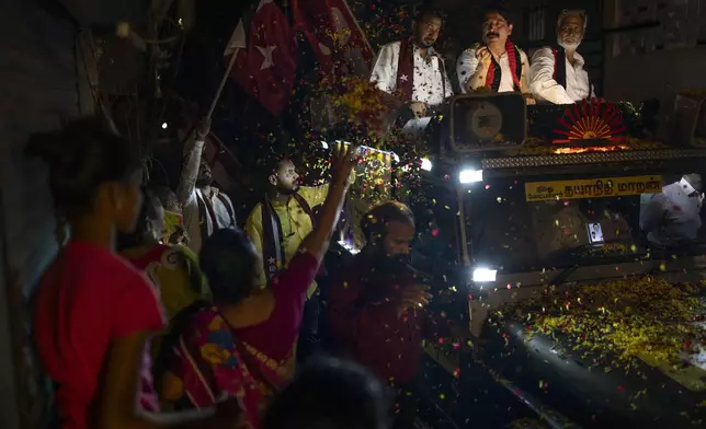 A woman showers flower petals as Dravida Munnetra Kazhagam (DMK) party candidate Dayanidhi Maran, center, rides on top of a vehicle during a roadshow ahead of country's general elections, in the southern Indian city of Chennai, April 14, 2024. (AP Photo/Altaf Qadri)