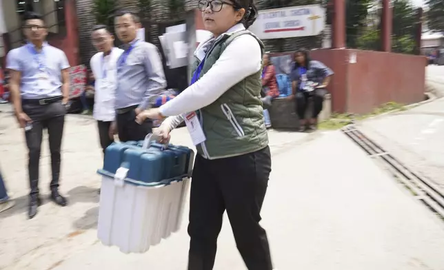 Presiding Officer Neichutuonuo Yhome, 27, carries an electronic voting machine and proceeds towards her polling station on the eve of polls in Kohima, in the northeastern Indian state of Nagaland, Thursday, April 18, 2024. (AP Photo/Yirmiyan Arthur)