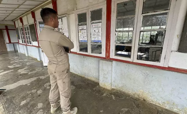 A policeman looks at election posters at a polling station on the eve of polling in Chedema village, in the northeastern Indian state of Nagaland, Thursday, April 18, 2024. (AP Photo/Yirmiyan Arthur)