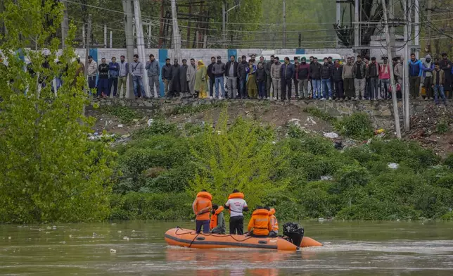 People watch rescuers of the National Disaster Response Force (NDRF) search after a boat carrying people including children capsized in Jhelum river on the outskirts of Srinagar, Indian controlled Kashmir, Tuesday, April. 16, 2024. Rescue operation is continuing for the several missing people. (AP Photo/Mukhtar Khan)