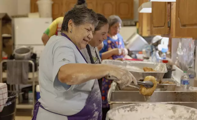 Carol Tiger, a member of Muscogee Nation and an elder at the Springfield United Methodist Church in Okemah, Okla., lets the oil drip off a freshly-cooked piece of frybread at the church's annual wild onion dinner on AprilA 6, 2024. Wild onions are among the first foods to grow in the spring, and the dinners have been a tradition in Native American communities for generations. (AP Photo/Brittany Bendabout)