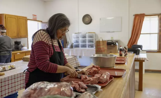 Members of the Springfield United Methodist Church in Okemah, Okla., prepare pork for cooking on April 5, 2024. Fried pork is an important dish at wild onion dinners in Oklahoma. The dinners are an annual tradition among tribal nations in the state originally from the southeastern U.S. (AP Photo/Brittany Bendabout)