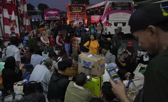 People wait for their buses as they leave for their hometowns ahead of the Eid al-Fitr holiday at Kalideres Bus Terminal in Jakarta, Indonesia, Saturday, April 6, 2024. Millions of Indonesians are packing bus and train stations, airports and highways as they head to hometowns to celebrate Thursday's Eid al-Fitr festival with family. (AP Photo/Dita Alangkara)