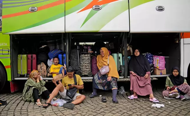 People wait for the departure of their buses to Central Java on a free trip home organized by Indonesian National Police ahead of Eid al-Fitr holiday in Jakarta, Indonesia, Saturday, April 6, 2024. Millions of Indonesians are packing bus and train stations, airports and highways as they head to hometowns to celebrate Thursday's Eid al-Fitr festival with family. (AP Photo/Dita Alangkara)